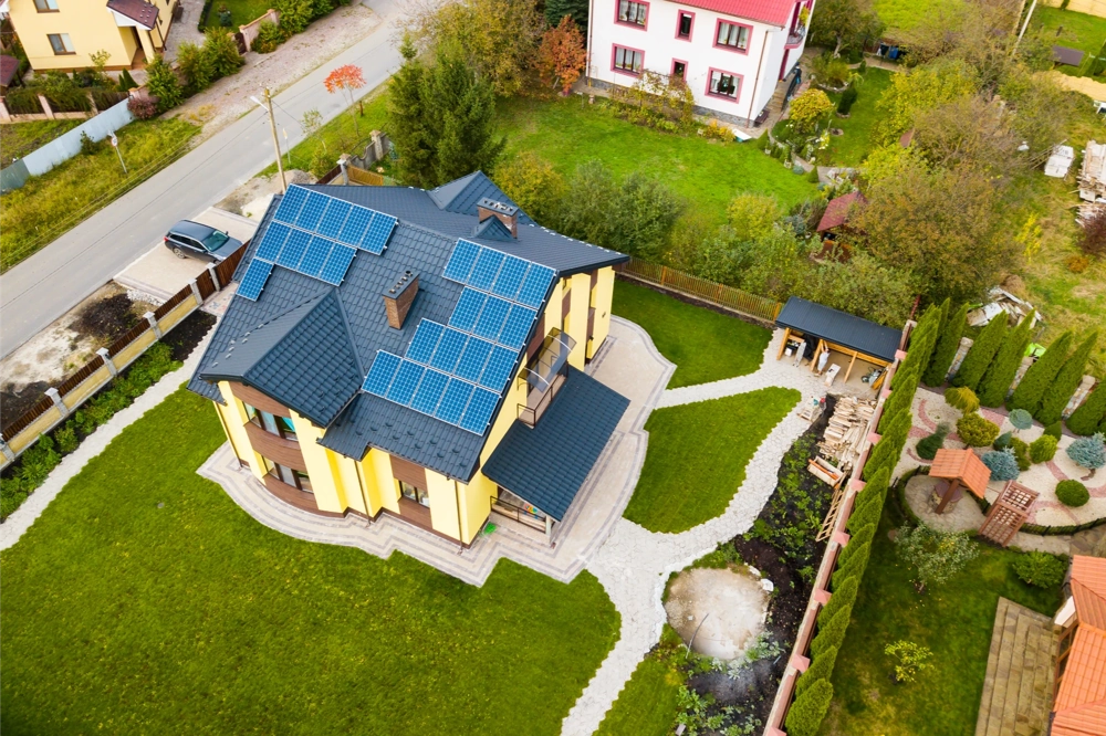 Installation de panneaux solaires sur le toit d’une maison moderne avec allée pavée et jardin soigné