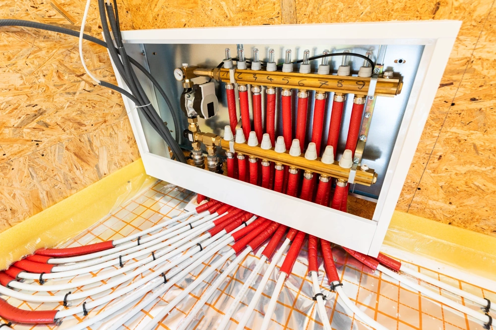 Collecteur de chauffage par le sol encastré avec plusieurs tubes PEX isolés rouge et blanc