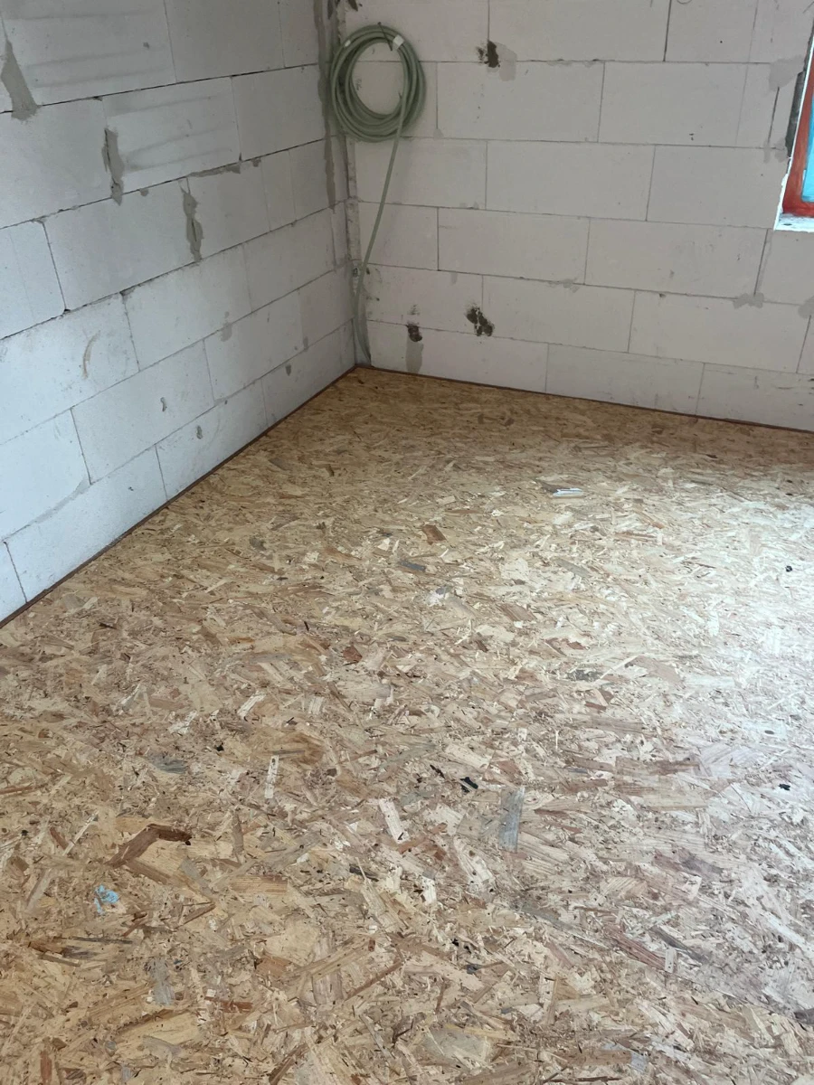 Pose de panneaux OSB en vue de parquet flottant dans une pièce en rénovation